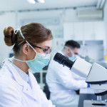 Team of experienced biologists working on microscopes in laboratory