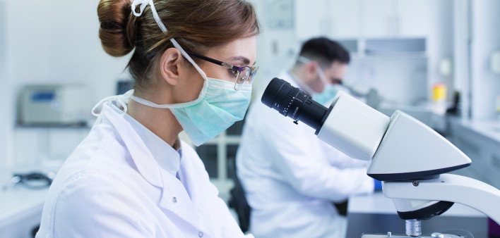 Team of experienced biologists working on microscopes in laboratory