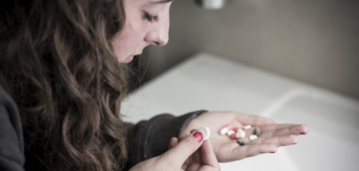 Teen girl holding a selection of pills