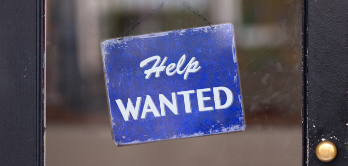 Help wanted sign hanging in window