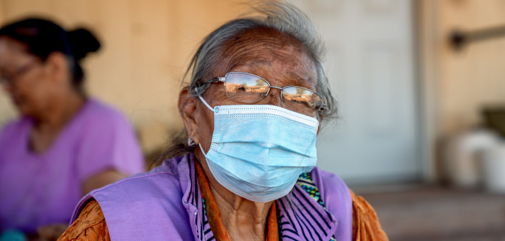 An elderly Navajo grandmother and Matriarch at her home, wearing a mask to protect her from coronavirus