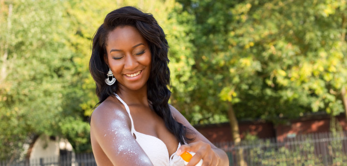 young woman applying sun cream at the beach