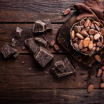 Cocoa beans and chocolate on wooden background