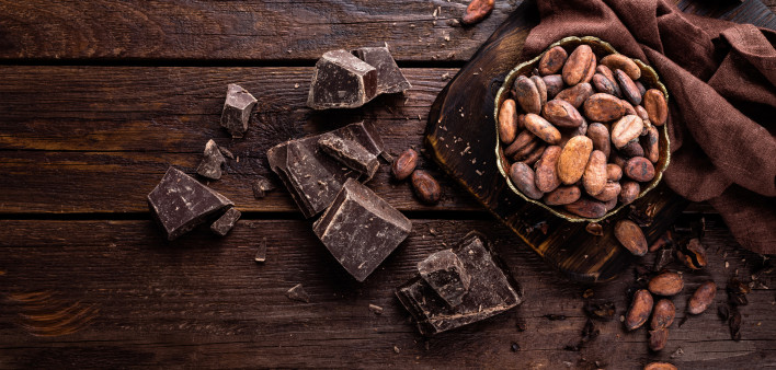 Cocoa beans and chocolate on wooden background