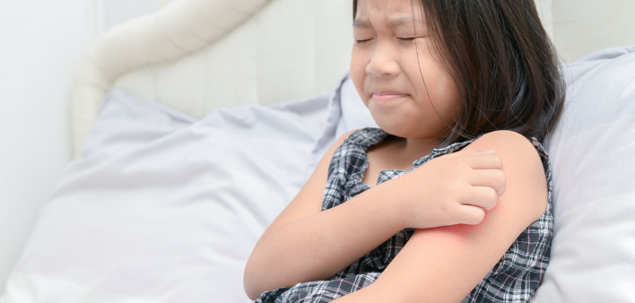 girl scratch the itch with hand sitting on bed,