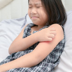 girl scratch the itch with hand sitting on bed,
