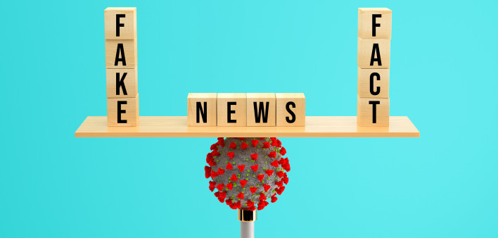 wooden scale balancing cubes with message FAKE, NEWS and FACT on a corona virus on colorful background