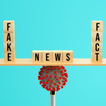 wooden scale balancing cubes with message FAKE, NEWS and FACT on a corona virus on colorful background