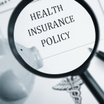 A maginfying glass looking at the words "Health Insurance Policy"