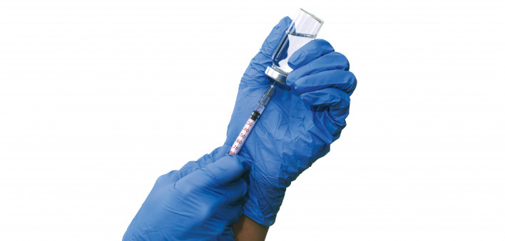 hands with blue gloved filling a syringe from a vial of vaccine