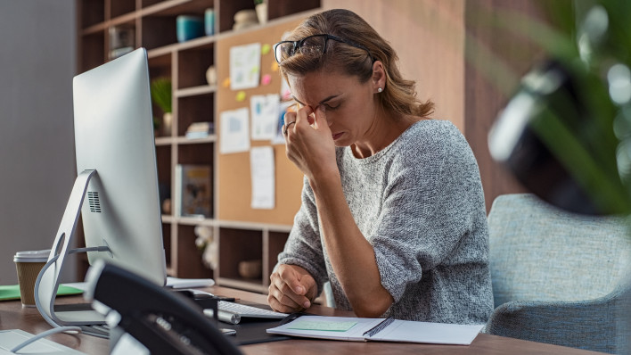 Exhausted businesswoman having a headache in modern office.