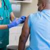 Nurse gives mature African American man a vaccination in doctor's office during coronavirus pandemic