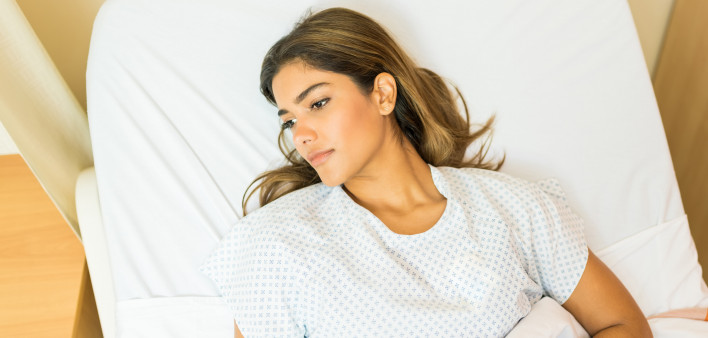 High angle view of thoughtful sick patient looking away while lying on hospital bed during treatment