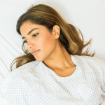High angle view of thoughtful sick patient looking away while lying on hospital bed during treatment