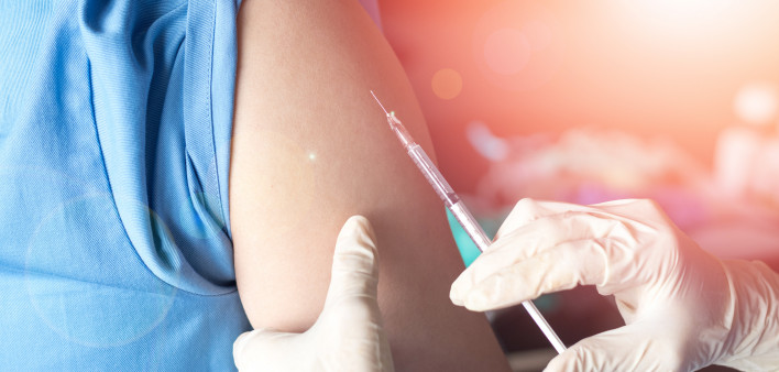 Vaccination healthcare concept. Hands of doctor or nurse in medical gloves injecting a shot of vaccine to a man patient.