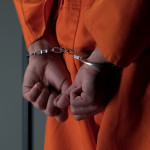 Prisoner with handcuffed arms behind back, another jail transfer, criminal