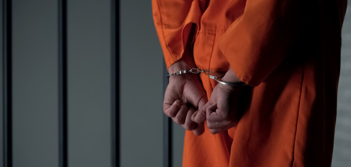 Prisoner with handcuffed arms behind back, another jail transfer, criminal