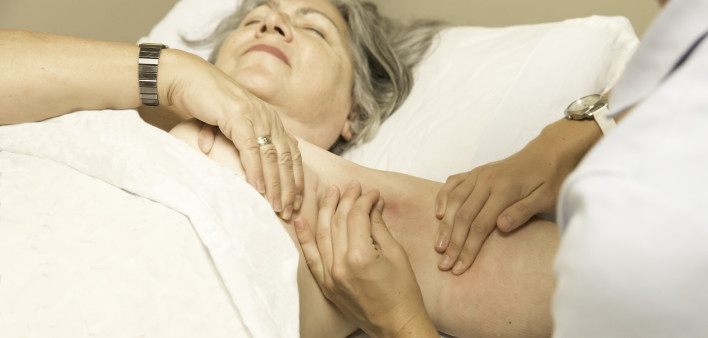 A woman's swollen arm is palpated by a doctor