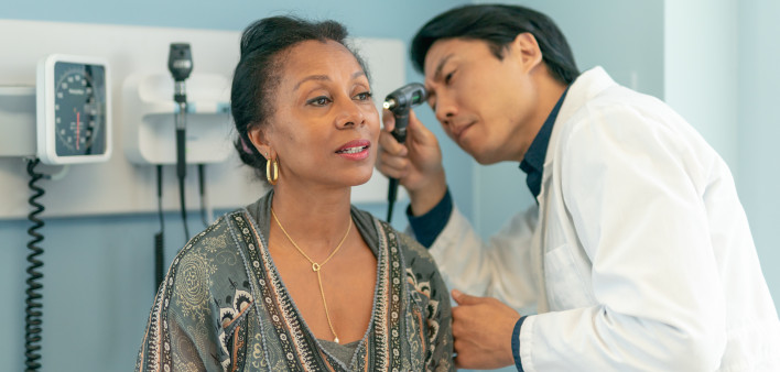 Mature adult woman has ears checked by doctor at routine medical appointment