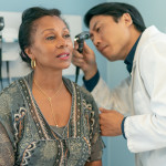 Mature adult woman has ears checked by doctor at routine medical appointment