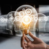 illustration of hand holding light bulb over head shapes and cogs