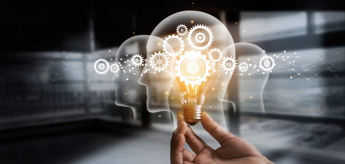 illustration of hand holding light bulb over head shapes and cogs