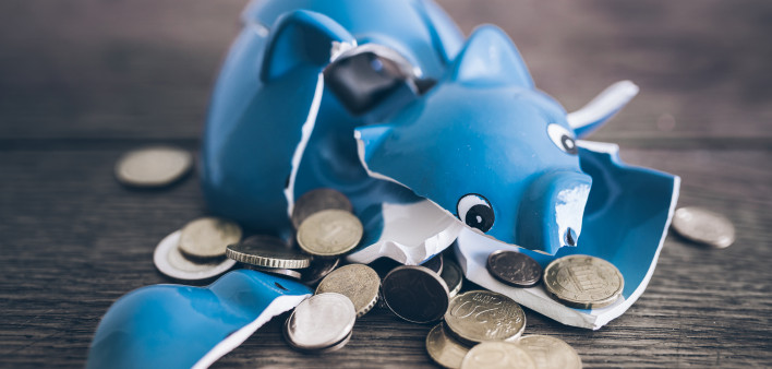 Shattered broken piggy bank with coins on rustic wooden table