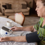 Grandmother is measuring her blood pressure on the living room