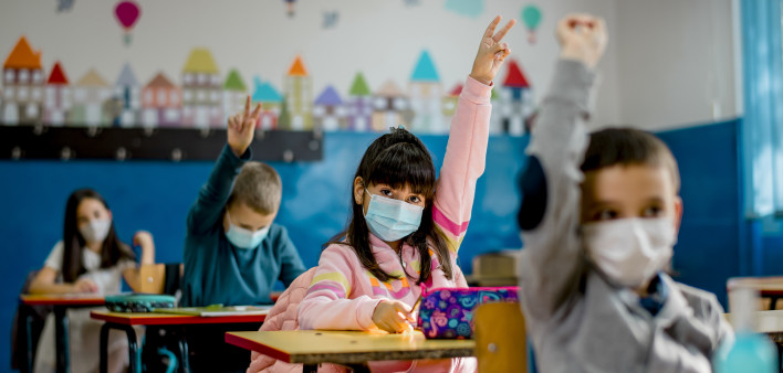 Elementary schoolchildren wearing a protective face masks in the classroom. Education during epidemic.