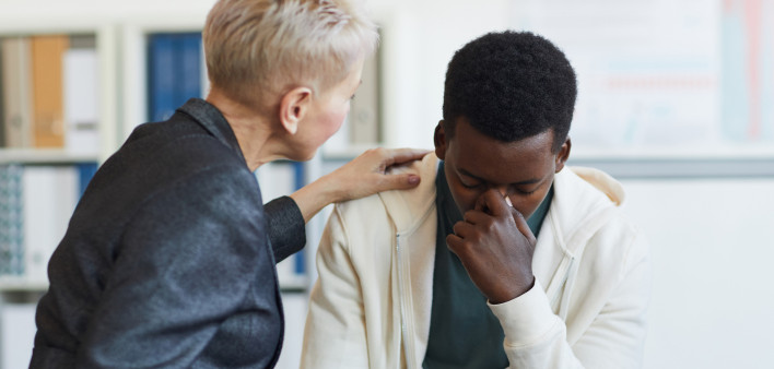 Save Crying Young Man in Support Group Portrait of young African-American man crying while sitting on chair in support group circle, copy space Grief Stock Photo Description  Portrait of young African-American man crying while sitting on chair in support 