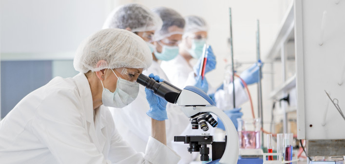 Scientists in protective suits in a science laboratory study a virus
