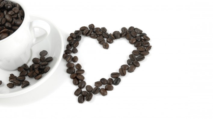 cup of coffe and coffee beans arranged in the shape of a heart