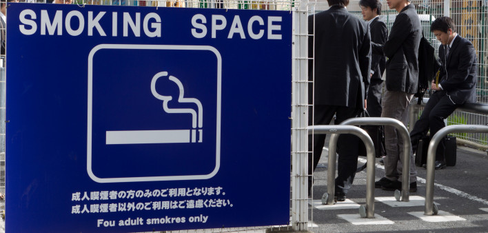 People smoke cigarettes at a smoking space in Tokyo, Japan.