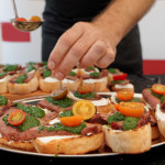 Chef is cooking bruschettas with beefsteak and pesto sauce