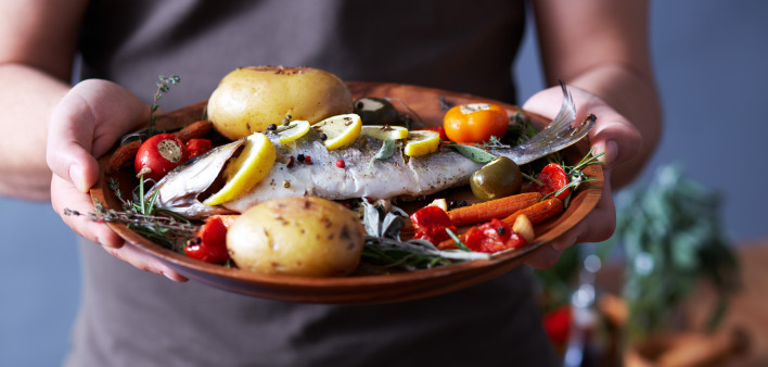 man holding plate of food fish