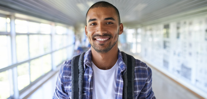 Portrait of a happy young man standing in a corridor on campus
