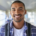 Portrait of a happy young man standing in a corridor on campus