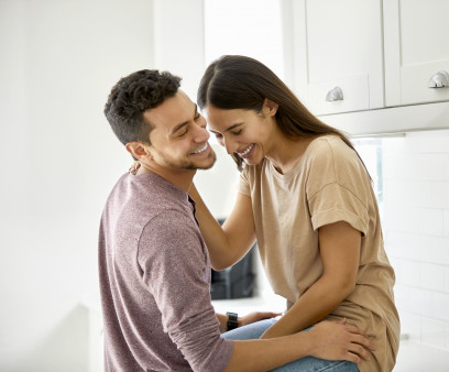 Cheerful Latino young couple talking in kitchen at home
