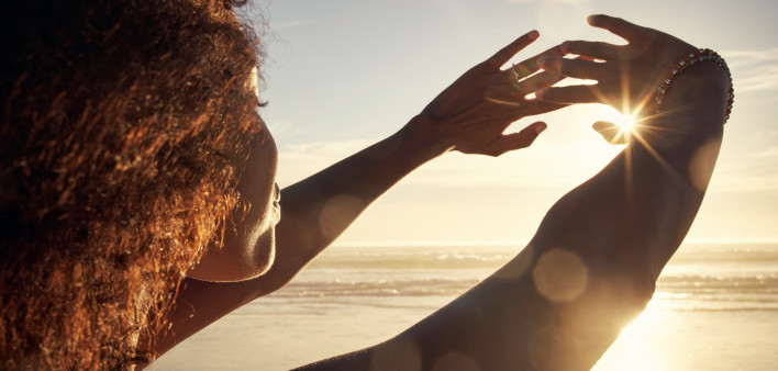 Rearview shot of a young woman blocking the sunlight with her hands at the beach