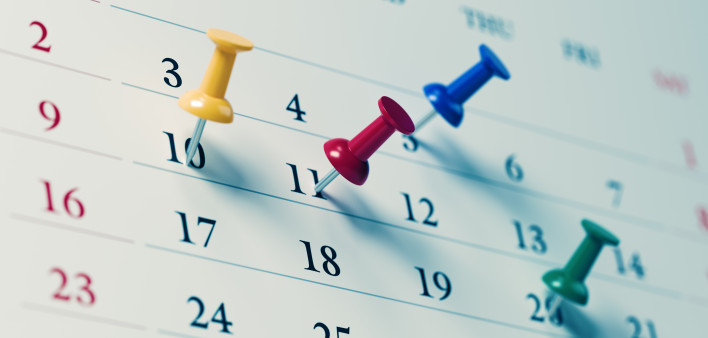 White calendar with colored push pins reminding important dates