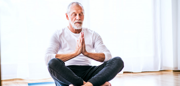 A contented senior man meditating at home.