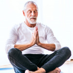 A contented senior man meditating at home.