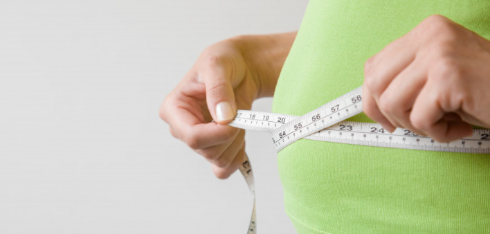 Fat overweight woman measuring her waist.
