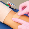 pink gloves putting band aid on arm after blood draw