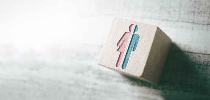 Trans symoby on wooden block half male half female gender neutral bathroom