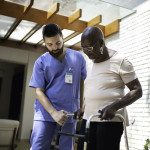 Home caregiver helping senior woman to walk
