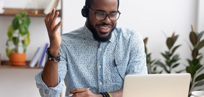 Smiling African American employee in headphones using laptop