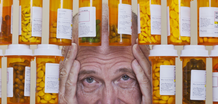 Depressed Senior Man Looking Through Rows of Prescription Medication
