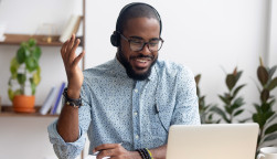 Smiling African American employee in headphones using laptop