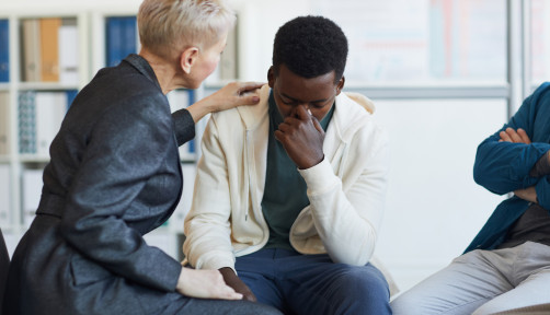 Save Crying Young Man in Support Group Portrait of young African-American man crying while sitting on chair in support group circle, copy space Grief Stock Photo Description  Portrait of young African-American man crying while sitting on chair in support 